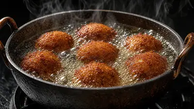 Bolinhos de feijão-fradinho sendo fritos em óleo borbulhante em panela de ferro em uma barraca de rua.